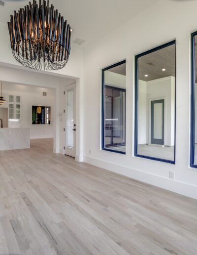 Modern spacious interior with large windows, wooden flooring, and a unique chandelier.