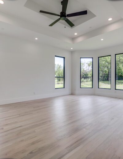 A spacious, empty room with large windows and hardwood flooring.