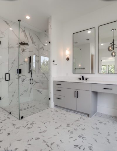 Modern bathroom interior with double vanity and glass shower enclosure.