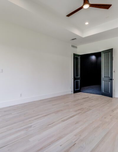 An empty room with light hardwood floors, white walls, and a ceiling fan.