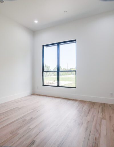 Empty modern room with laminate flooring and a large window.