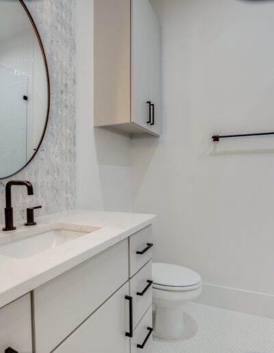 Modern bathroom with white vanity, round mirror, and walk-in shower.
