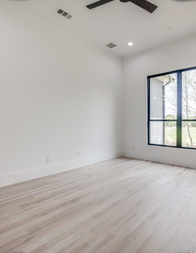 Empty room with a large window and wooden flooring in a new house.