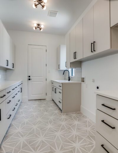 Modern kitchen with white cabinetry, geometric backsplash, and patterned flooring.