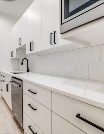 A modern kitchen with white cabinetry, stainless steel appliances, and hexagonal backsplash tiles.