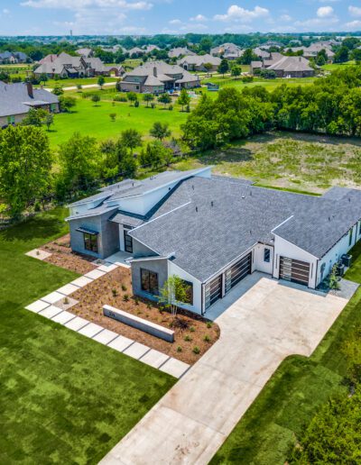 Aerial view of a modern single-story house with a large yard and surrounding neighborhood.