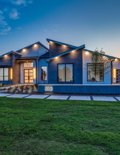 Modern suburban home illuminated at twilight with landscaped front lawn.