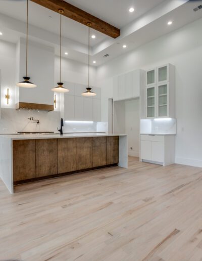 Modern kitchen interior with white cabinetry, wooden accents, and hardwood floors.