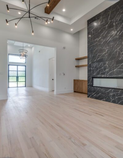 Modern living room interior with a fireplace, wood flooring, and high ceiling.