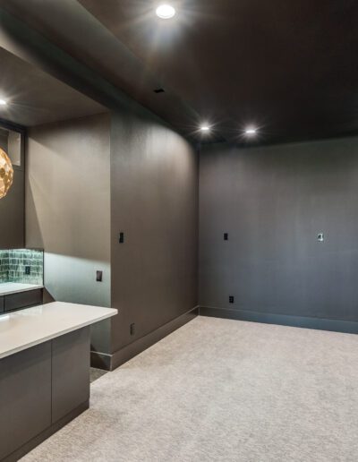 A modern home bar area with a pendant light and dark gray cabinetry.
