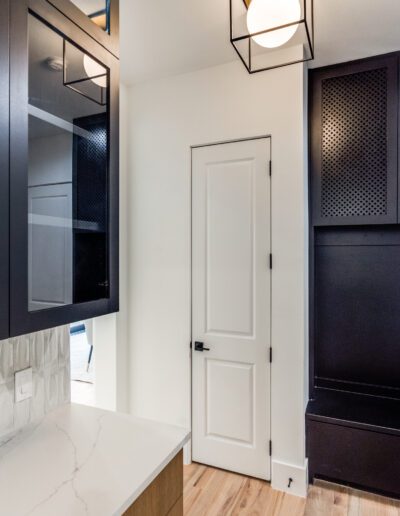 Modern bathroom interior with a marble countertop, white door, black cabinets, and stylish pendant lights.