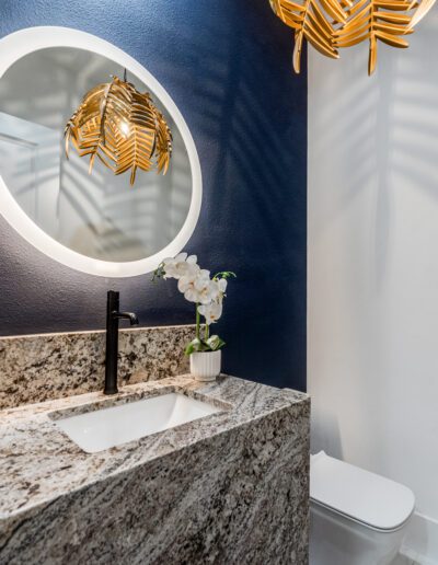 Modern bathroom interior with granite countertop and decorative mirror.