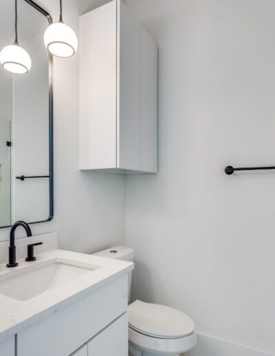 Modern bathroom interior with white vanity, wall-mounted cabinet, and orchid decoration.