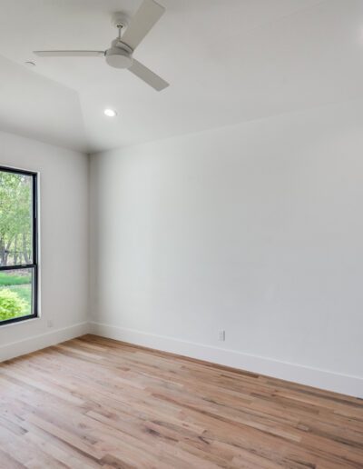 Bright, empty room with large window and hardwood floors.