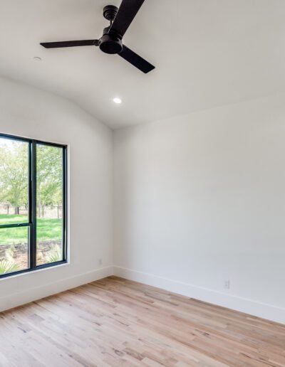 Bright, empty room with large window and hardwood floor.
