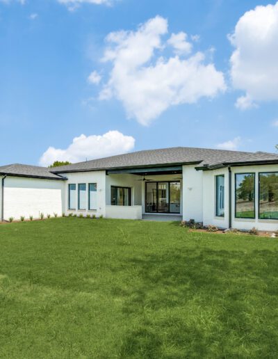 Modern single-story home with large windows and a well-manicured lawn.